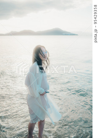 海辺で音楽を聴く女性の写真 95429358