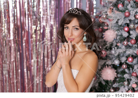 Beautiful caucasian woman decorates christmas tree indoors. Christmas Beautiful caucasian woman decorates christmas tree indoors. Christmas 95429402