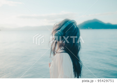 海辺で音楽を聴く女性の写真 95429751