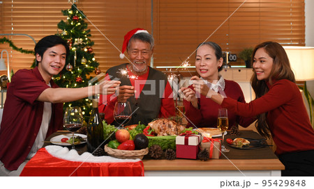 Joyful group of people with sparklers celebrating Christmas together in cozy home. Celebration, holidays and Christmas concept Joyful group of people with sparklers celebrating Christmas together in cozy home. Celebration, holidays and Christmas concept 95429848