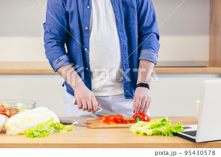 Close-up, hands of young man preparing at home in the kitchen fresh vegetables and fruits, healthy food 95430578