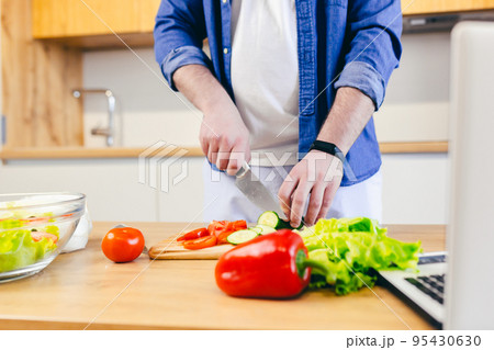 Close-up, hands of young man preparing at home in the kitchen fresh vegetables and fruits, healthy food Close-up, hands of young man preparing at home in the kitchen fresh vegetables and fruits, healthy food 95430630