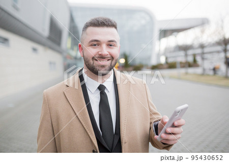 young handsome businessman goes to the airport with a suitcase talks on the phone, smiles, calls a taxi, looking for. waiting for a meeting 95430652