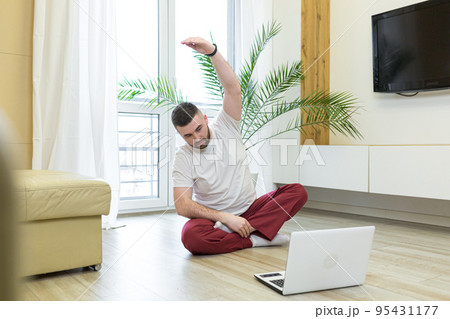 young man is engaged in yoga, fitness, sports at home online from a laptop, teaches, studies, quarantined, remotely, smiles, leads a healthy lifestyle young man is engaged in yoga, fitness, sports at home online from a laptop, teaches, studies, quarantined, remotely, smiles, leads a healthy lifestyle 95431177