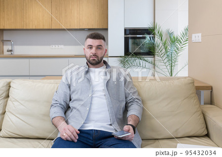 Young man at home sitting on the couch, using the phone, talking on the phone, talking on video 95432034