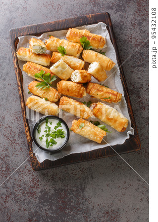 Sigara Boregi Turkish Cigar Shaped Rolls stuffed with cheese and herbs closeup on the wooden board. Vertical top view 95432108