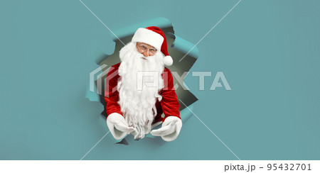 Emotianal Santa Clause spread arms in forward through paper hole. Advertisement concept 95432701