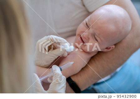 Pediatric doctor injecting the vaccine to the newborn 95432900