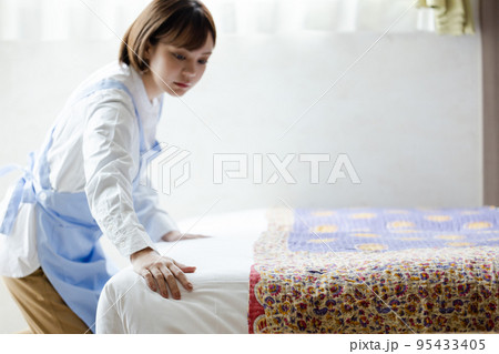 ベッドメイクをする可愛い女性 95433405
