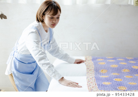 ベッドメイクをする可愛い女性 95433428