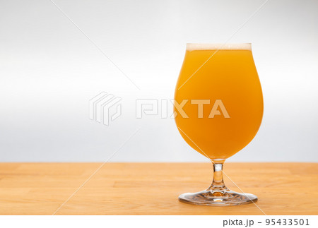 Full tulip glass of NEIPA ale beer on a table Full tulip glass of NEIPA ale beer on a table 95433501