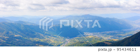 mountainous rural landscape of transcarpathia. kolochava village down in the valley observed from the top of a hill. distant ridge beneath a cloudy sky. nature scenery in morning light 95434611