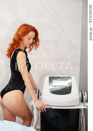 Red-haired woman in a medicine salon, anti-cellulite procedure. Red-haired woman in a medicine salon, anti-cellulite procedure. 95436096