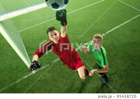 Soccer goalkeeper in action on soccer stadium. Goalkeeper hits the ball in jump in front of gates. Stadium made in 3D. Sport competition, energy. Soccer goalkeeper in action on soccer stadium. Goalkeeper hits the ball in jump in front of gates. Stadium made in 3D. Sport competition, energy. 95438720