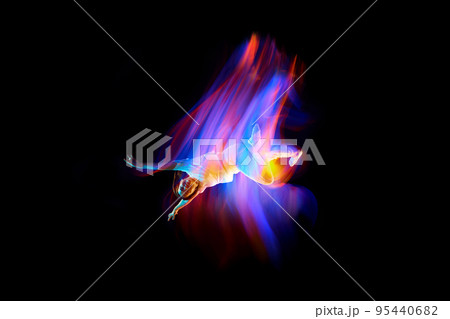 Dance in motion. Studio shot of flying, jumping dancer or gymnast performing tricks in the air over black background with mixed neon glowing rays 95440682