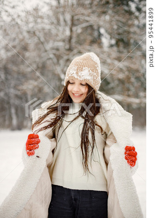 Girl spending time in the winter park. Teenager posing for a photo. Girl wearing warm jacket and knitted hat. Girl spending time in the winter park. Teenager posing for a photo. Girl wearing warm jacket and knitted hat. 95441899