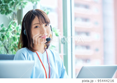 コールセンターで働くカメラ目線の若い女性オペレーター コールセンターで働くカメラ目線の若い女性オペレーター 95444216