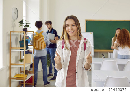 Happy school, college or university student standing in classroom and giving thumbs up Happy school, college or university student standing in classroom and giving thumbs up 95446075