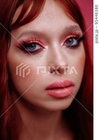 Beautiful young woman with red hair and bright pink makeup on a pink background. Woman touching her lips with her hand Beautiful young woman with red hair and bright pink makeup on a pink background. Woman touching her lips with her hand 95446380