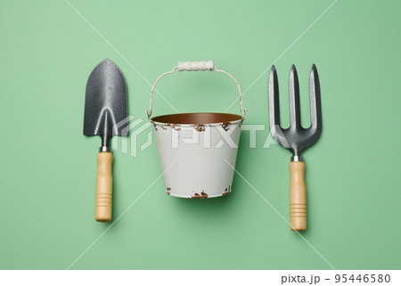 Miniature garden tools in a metal bucket on a green background, top view Miniature garden tools in a metal bucket on a green background, top view 95446580