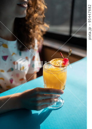 female drink fresh tequila sunrise orange cocktail with slice of citrus in bar 95447682