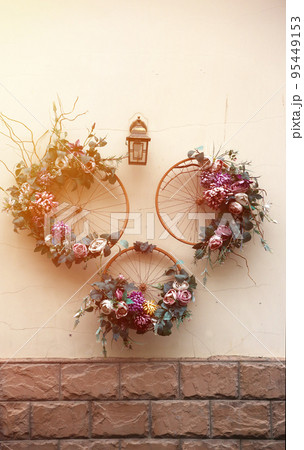 Decoration urban art object from bicycle wheels and flowers on wall 95449153
