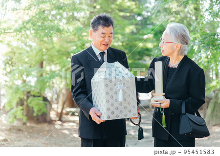 お葬式で火葬した遺骨を持つ日本人の高齢者夫婦 95451583