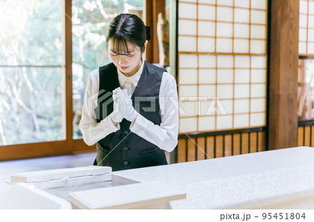 ご遺体に合掌する葬儀スタッフ・納棺師の女性 95451804