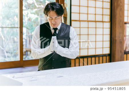 ご遺体に合掌する葬儀スタッフ・納棺師の男性 95451805