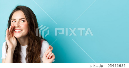 Cunning silly woman spread gossips, talking quiet, telling rumour, smiling and giggle at right side, standing over blue background Cunning silly woman spread gossips, talking quiet, telling rumour, smiling and giggle at right side, standing over blue background 95453685