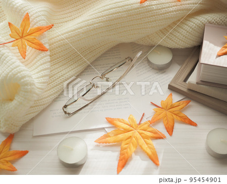 木目背景にニットと紅葉と本を置いた読書の秋のイメージ 95454901