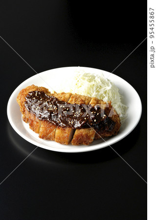 味噌ベースのソースがかかった豚カツとキャベツの千切りを黒背景で撮影 味噌ベースのソースがかかった豚カツとキャベツの千切りを黒背景で撮影 95455867