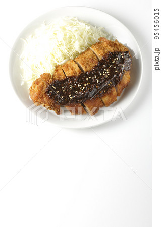 味噌ベースのソースがかかった豚カツとキャベツの千切りを白背景で俯瞰撮影 95456015