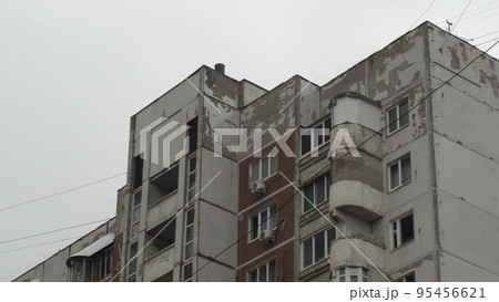 Concrete panel building close-up. The old building of the former USSR. Third world country. A tattered building against a backdrop of gray clouds. Concrete panel building close-up. The old building of the former USSR. Third world country. A tattered building against a backdrop of gray clouds. 95456621