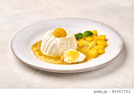 Panna cotta with natural vanilla pod, mango syrup and mint, italian food 95457752