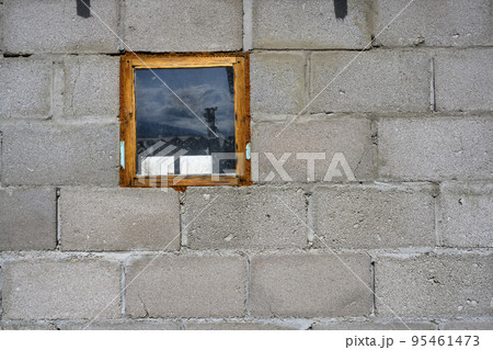 A rough cinder block wall with a small window reflecting the sky of Kyrgyzstan A rough cinder block wall with a small window reflecting the sky of Kyrgyzstan 95461473