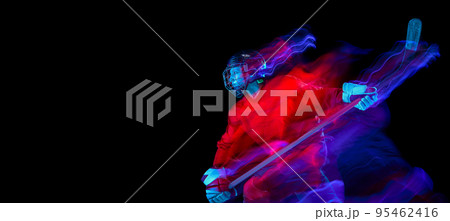 Dynamic portrait of energetic hockey player training with hockey stick isolated over dark background in mixed neon glow. Art, sport, action, motion Dynamic portrait of energetic hockey player training with hockey stick isolated over dark background in mixed neon glow. Art, sport, action, motion 95462416