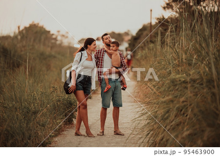 The family walks an idyllic path surrounded by tall grass. Selective focus The family walks an idyllic path surrounded by tall grass. Selective focus 95463900