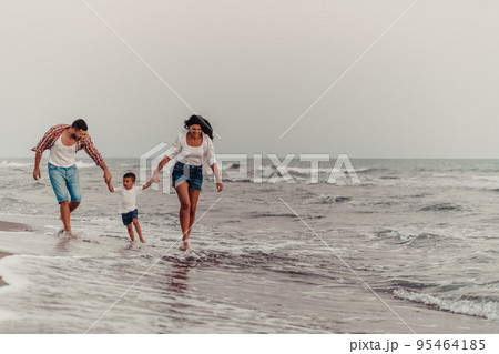 The family enjoys their vacation as they walk the sandy beach with their son. Selective focus  95464185