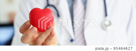 Man doctor hold red plastic heart and posing with stethoscope on neck Man doctor hold red plastic heart and posing with stethoscope on neck 95464627