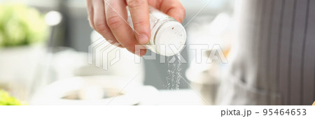 Professional cook hold saltcellar and add salt to soup against kitchen background Professional cook hold saltcellar and add salt to soup against kitchen background 95464653