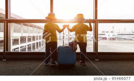 Child with suitcase at airport terminal waiting for departure looking out the window. Child with suitcase at airport terminal waiting for departure looking out the window. 95466077