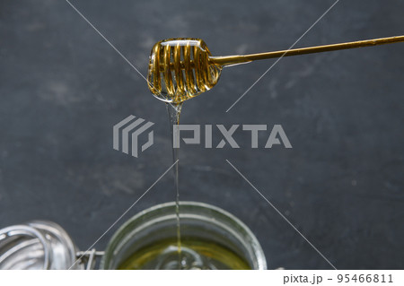 Glass jar full of honey with metal honey dipper on dark rustic background 95466811
