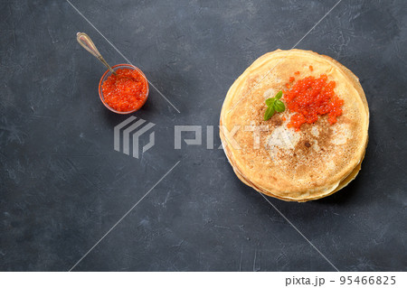 Stack of pancakes with red caviar on dark rustic background, top view with free text space 95466825