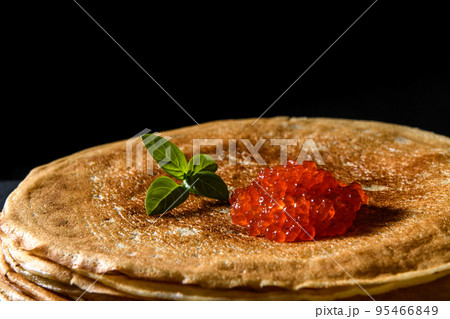 Stack of pancakes with red caviar on black background, close up 95466849