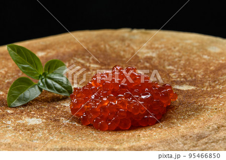 Stack of pancakes with red caviar on black background, close up 95466850