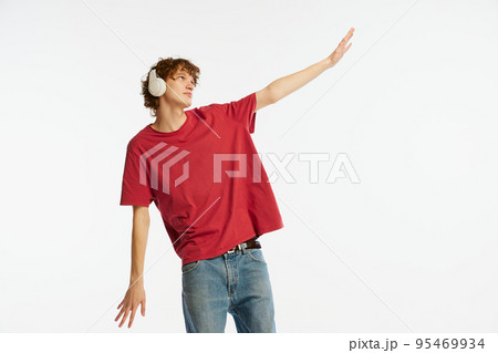 Dreaming young man, student in red tee and headphones isolated on white background. Concept of emotions, facial expression, youth, music 95469934