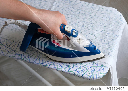 Housework and household concept. Husband doing clothing ironing at home. Male hand is ironing clothes, close up. Housework and household concept. Husband doing clothing ironing at home. Male hand is ironing clothes, close up. 95470402