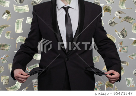 Poor person with empty pockets under money rain on grey background Poor person with empty pockets under money rain on grey background 95471547