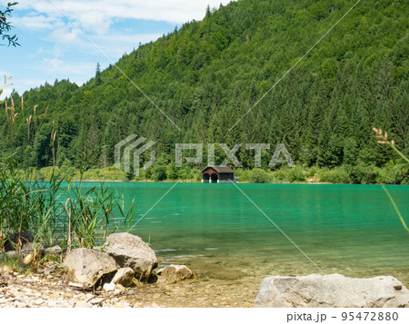 Fisher boat house and wooden hut with pier in the shore of Walchensee lake 95472880